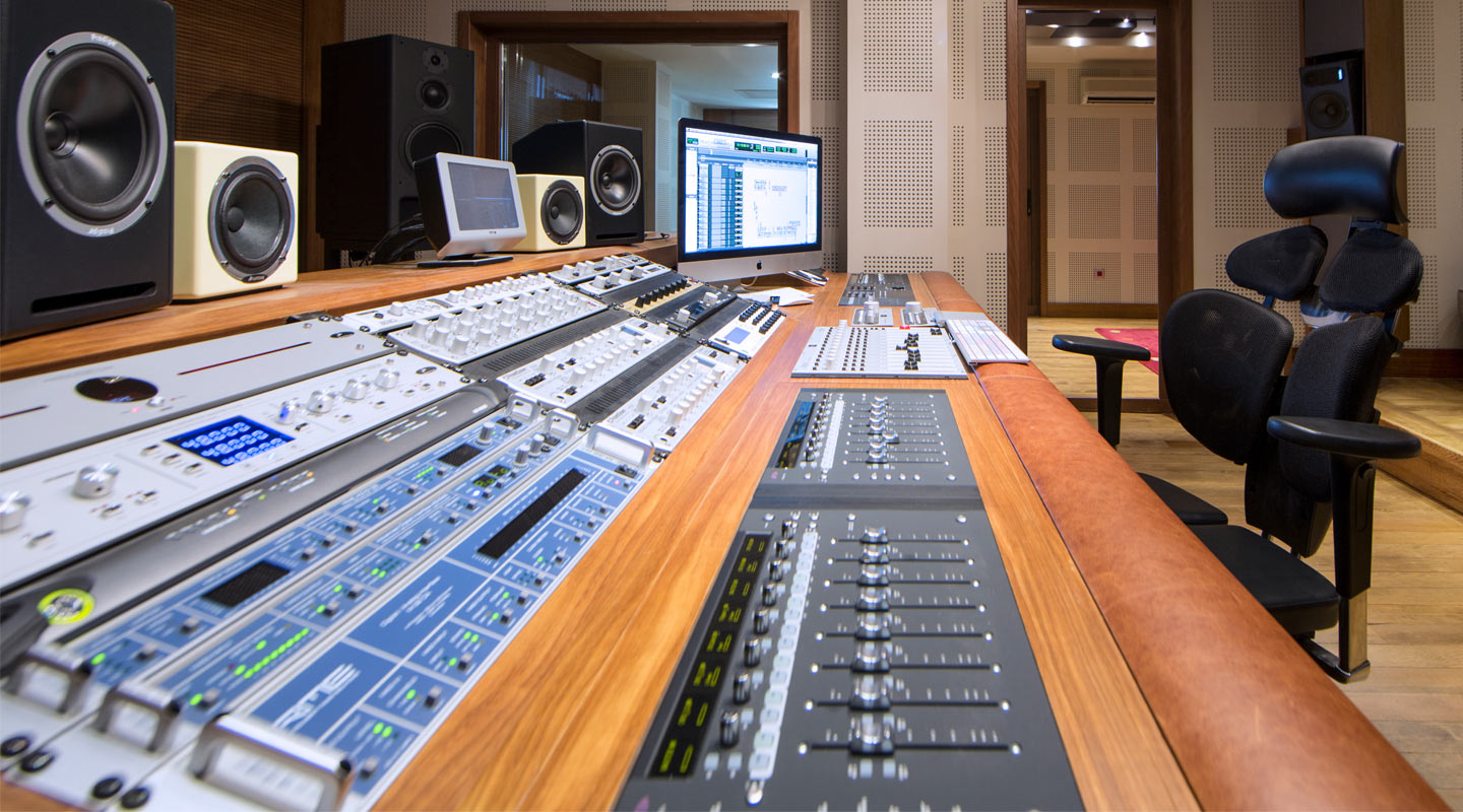 Side view of a mixing console and MADI rack gear in a recording studio 