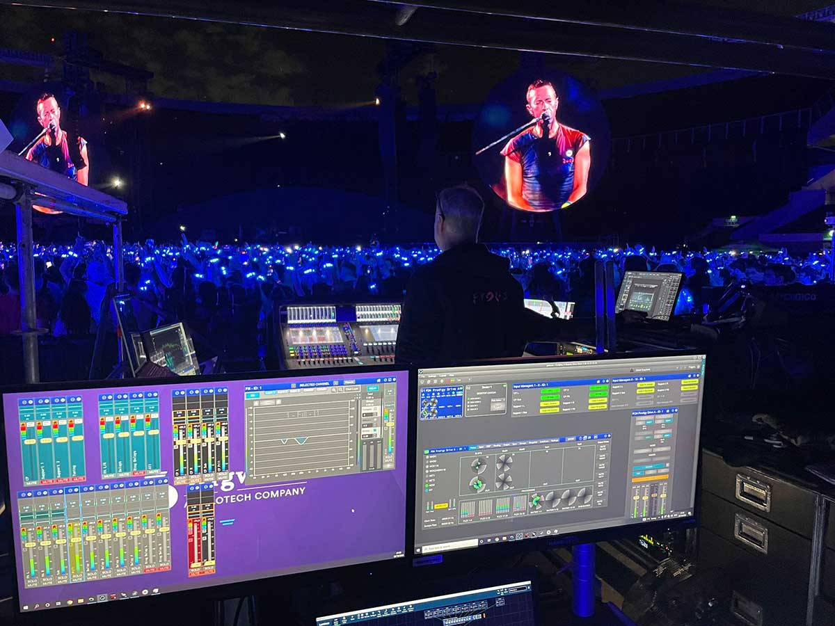 Computer screens behind the front of house console at a Coldplay concert