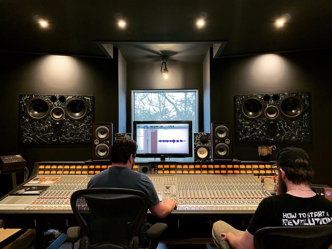 Two people in front of an SSL mixing console and Dynaudio speakers in The Friary Studio A